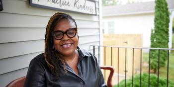 Donelle sitting in front of her house smiling.
