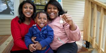Jessica smiling and hugging her two children, 15-year-old Amiyah and 1-year-old Noa, on the porch of their home.