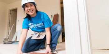 A young woman in a blue shirt laying flooring.