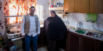 woman standing in a kitchen with an engineer from habitat