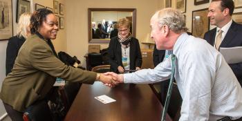 Two people shaking hands in office setting.