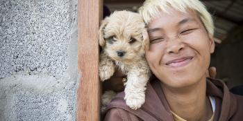 Woman smiling with a puppy in her doorway.