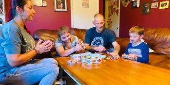 Family of four playing a board game in their living room.