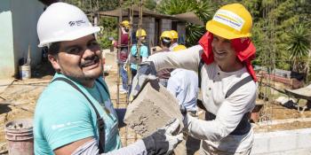 Two volunteers on a Global Village trip in Mexico holding a cement block on a build site.