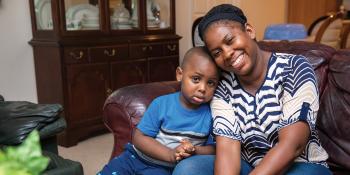 Mother and young son sitting together on their couch.