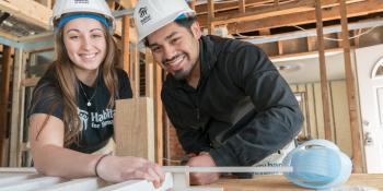 Young woman and young man smiling while working on a Collegiate Challenge build.