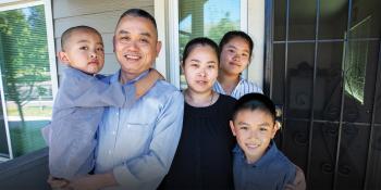 Family of five standing together on their front porch.