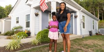 Mother and daughter hug in front of their Habitat home