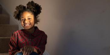 young Black girl sitting on her stairs and smiling.