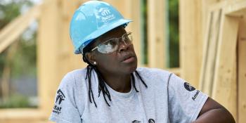 AmeriCorps member woman wearing hardhat and safety glasses on build site.