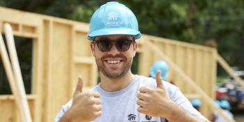 Man wearing Habitat AmeriCorps shirt, hardhat and sunglasses gives two thumbs up