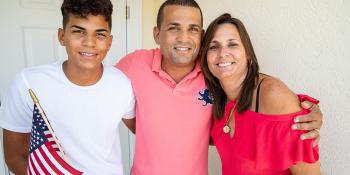 A family stands in front of their home.