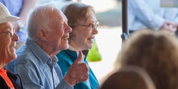 Jimmy Carter giving thumbs up next to Rosalynn Carter smiling.