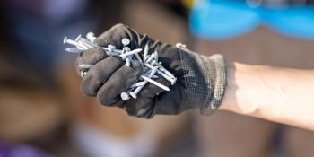 Close-up of gloved hand holding a handful of nails