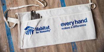 Close-up of toolbelt that has Habitat logo and the text "every hand makes a difference" printed on it