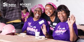 Three women volunteers in purple shirts smiling. 