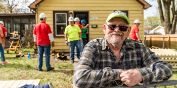 Robert standing in front of his home with volunteers in the background.