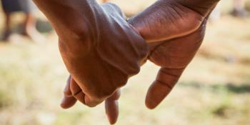 Close up of two people holding hands.