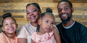 Mom and Dad smiling with their two young daughters