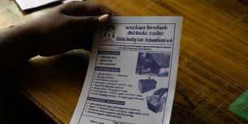 hand holding a flyer with the words "Raksha Roofing Loan" at the top
