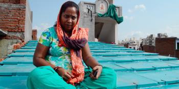 Woman in India sitting on her new ReMaterials roof.