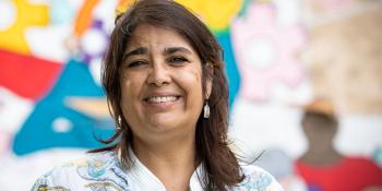 Woman smiling in front of colorful mural.