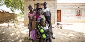 The Musonda family in front of their new home in Zambia built with the support of Habitat International and achieved through the Solid Ground Campaign.