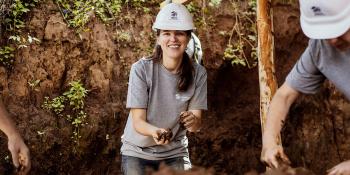 Young woman in hard hat working with mud.