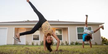 two children cartwheeling in front yard.