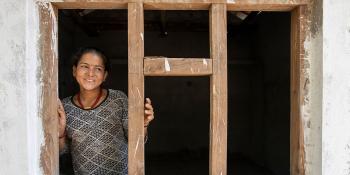 Nepal woman homeowner smiling in the framing of her future Habitat home.