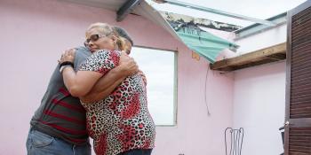 Two people hugging in damaged home