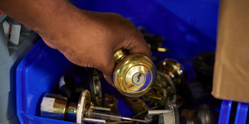 A hand putting a doorknob into a bin with other doorknobs for sale.