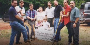 Group with shovels and large donation check on build site