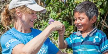 Woman volunteer fist bumping with kid in Guatemala on Global Village trip site.