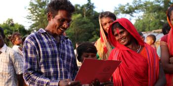 Smiling family holding land tenure document.