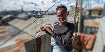A woman on a patio plays a flute.