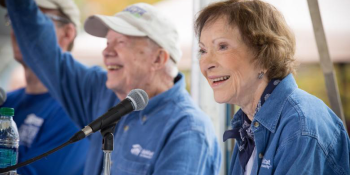 Jimmy and Rosalynn Carter in front of microphones smiling and waving