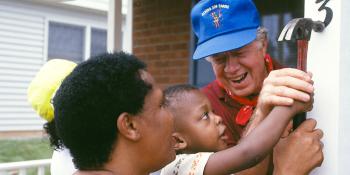 President Carter working with a child to hammer on his address number.