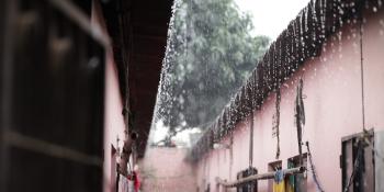 Photo of raindrops falling off a roof of a home in an informal settlement.