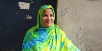 Smiling woman in colorful yellow, green and blue hijab.
