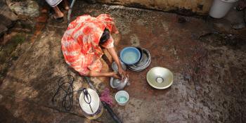 A woman washing dishes outside.