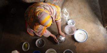 Overhead shot of woman washing cooking dishes on the floor of her home.