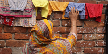 Woman in yellow hijab hanging clothes on a line.