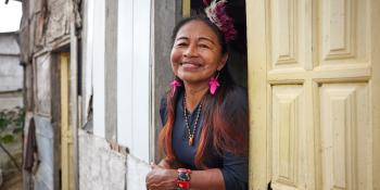 A woman smiles from a window with yellow panes.