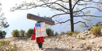 Person carrying items in mountainous landscape.