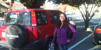 Red CRV and a woman standing next to it in a purple sweater.