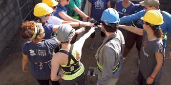 Group of volunteers putting their hands in a circle on a work site.