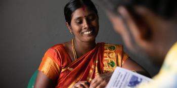 A woman smiles as she sits across from a colleague.