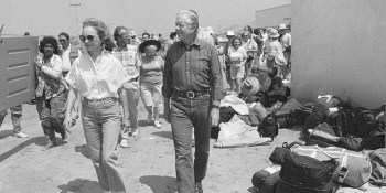 President and Mrs. Carter walking with a crowd of volunteers.