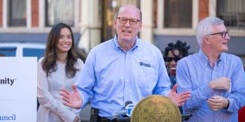 Habitat CEO Jonathan Reckford speaking at a lectern displaying the seal of the city of New York. Several other speakers at the ceremony stand behind him.